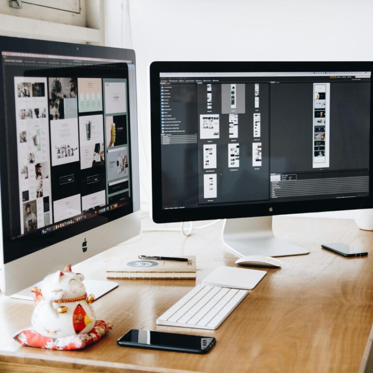 two-imac-s-with-keyboard-and-phones-on-desk